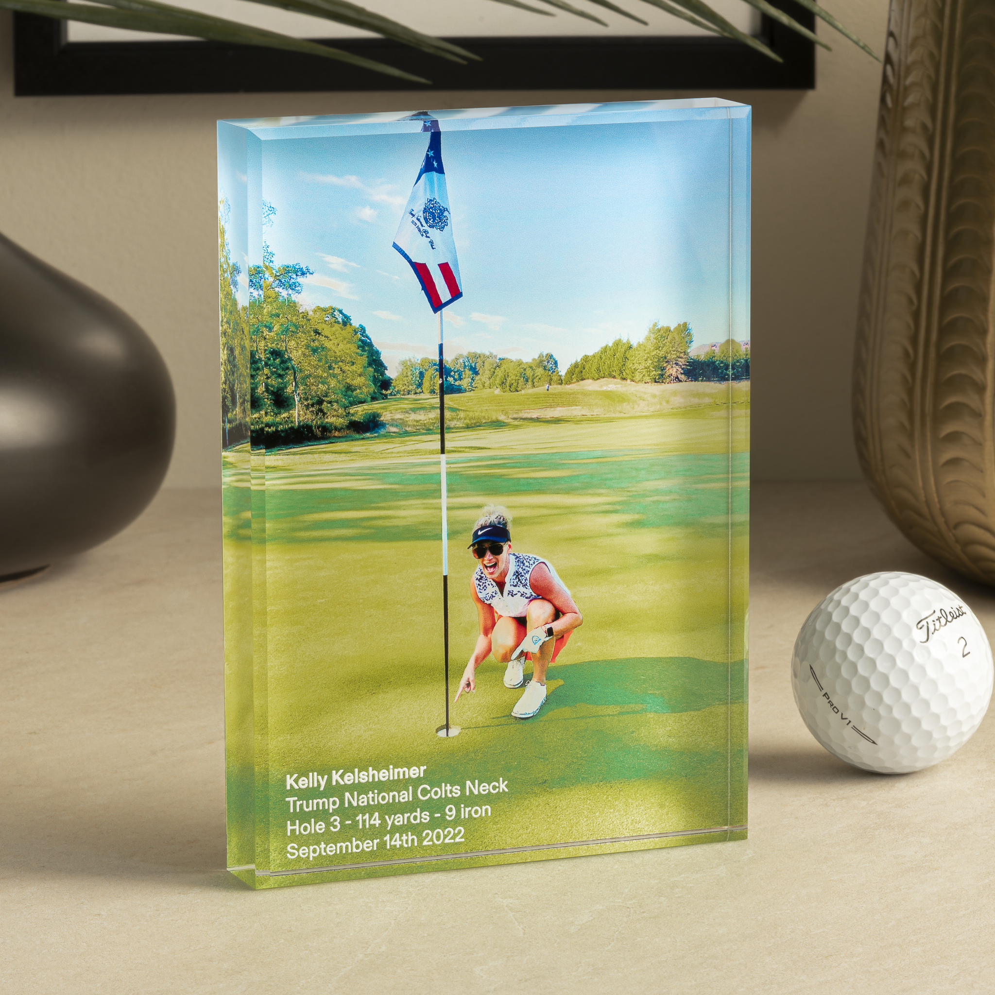 a glass trophy with a golf ball and a picture of a woman on the golf course